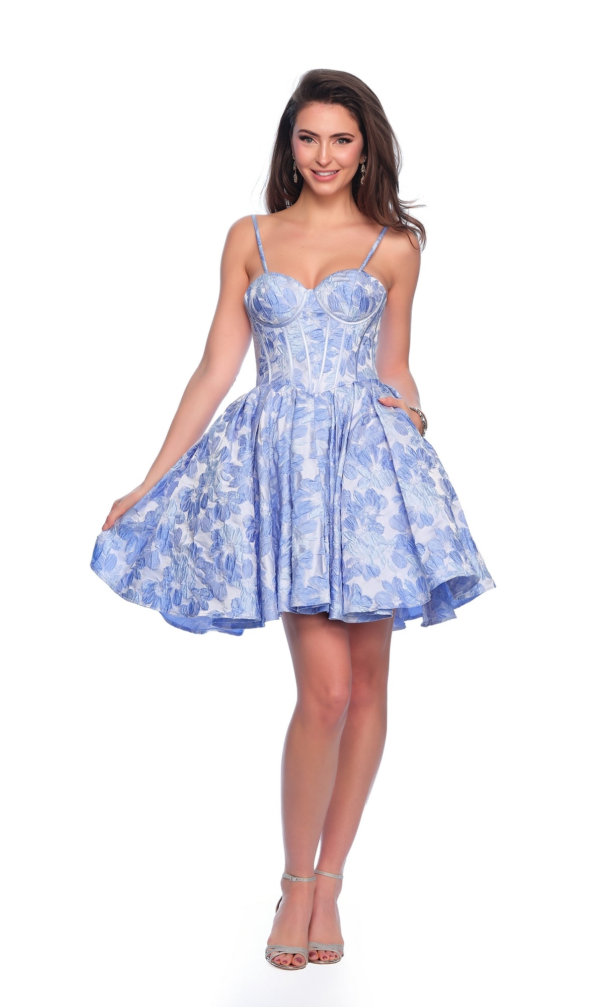 A woman models the Dave & Johnny Blue Floral Homecoming Dress 11960, featuring a fitted bodice and flared skirt, against a white background.
